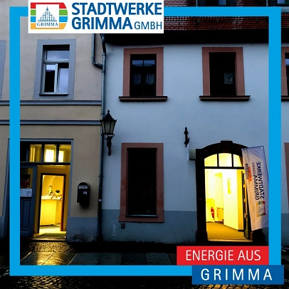 zwei hell erleuchtete Eingangstüren von dem Büro der Stadtwerke Grimma in der Dämmerung.