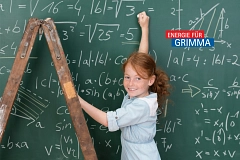 ein rothaariges Mädchen steht vor einer Schultafel voller Mathegleichungen